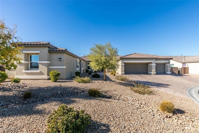 mediterranean / spanish home featuring a tile roof, driveway, an attached garage, and stucco siding