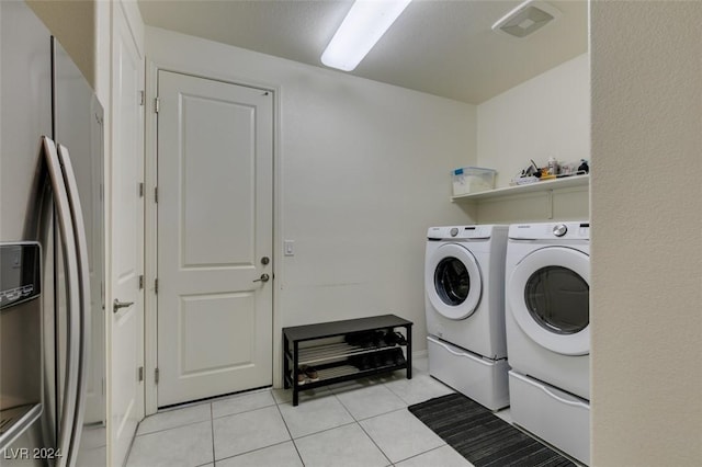 clothes washing area with washing machine and clothes dryer and light tile patterned floors