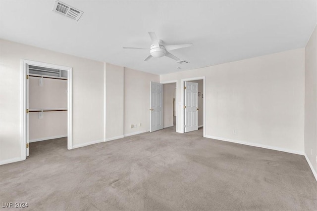 unfurnished bedroom featuring carpet, ceiling fan, a spacious closet, and a closet