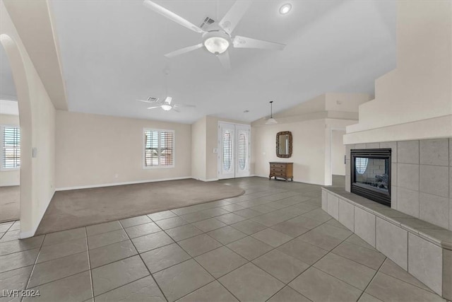 unfurnished living room with ceiling fan, light carpet, and a tiled fireplace