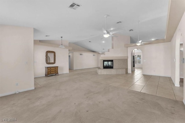 unfurnished living room featuring lofted ceiling, ceiling fan, light tile patterned floors, and a fireplace