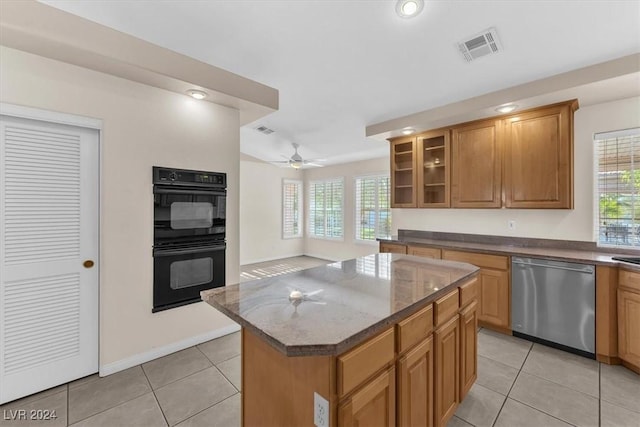 kitchen featuring dishwasher, light tile patterned flooring, double oven, dark stone counters, and a kitchen island