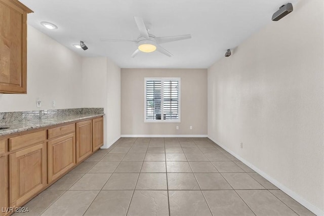 kitchen with light stone countertops, ceiling fan, and light tile patterned flooring