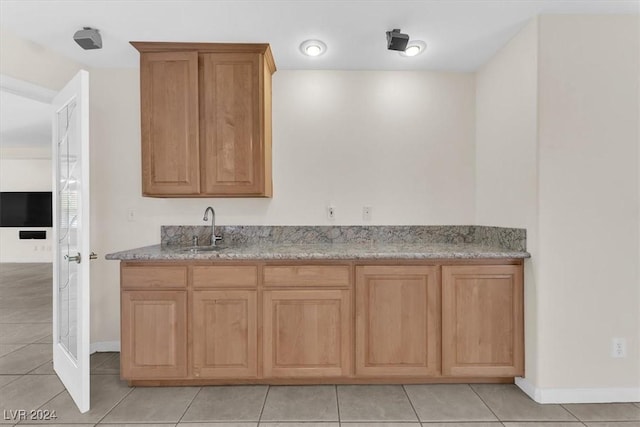 kitchen featuring light tile patterned flooring, light stone countertops, and sink