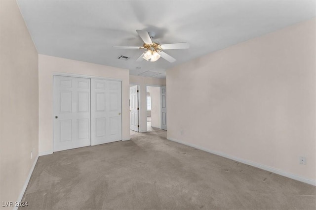 unfurnished bedroom featuring ceiling fan, light carpet, and a closet