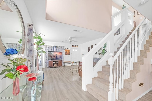 staircase featuring wood-type flooring and ceiling fan