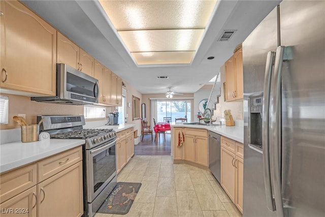 kitchen with kitchen peninsula, sink, light brown cabinets, and appliances with stainless steel finishes