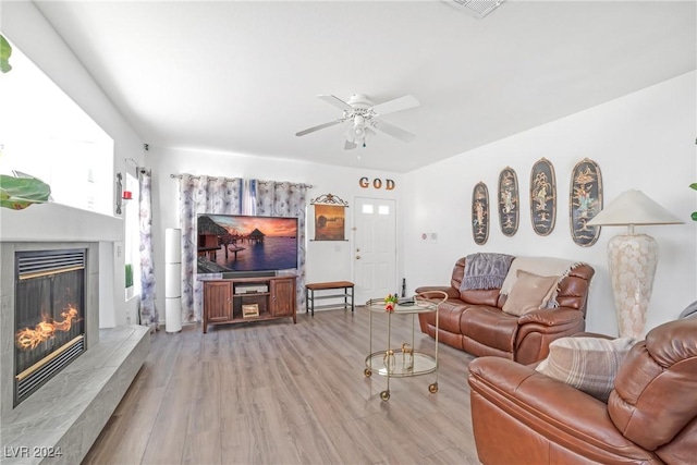 living room with ceiling fan, light hardwood / wood-style floors, and a fireplace