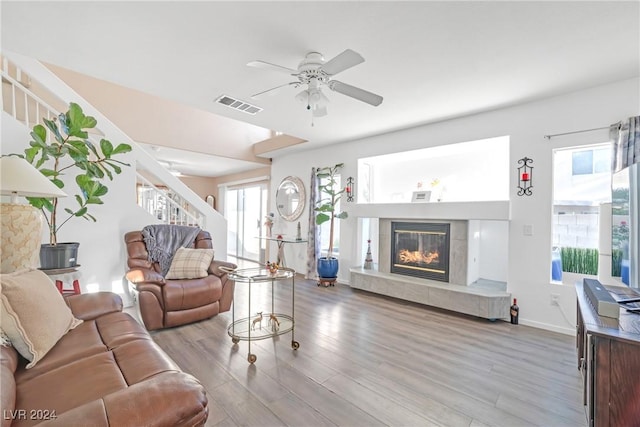 living room with light hardwood / wood-style floors, ceiling fan, and a tiled fireplace