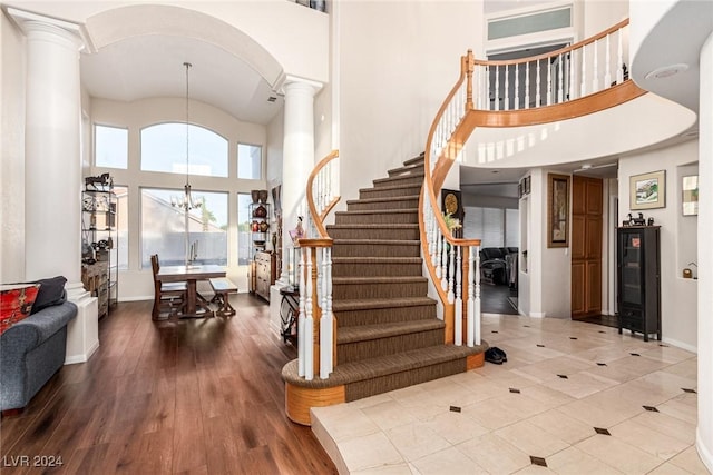 foyer entrance featuring decorative columns, a chandelier, a high ceiling, and hardwood / wood-style flooring