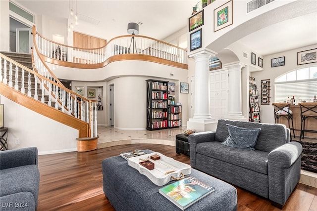 living room featuring ornate columns, dark wood-type flooring, and a high ceiling