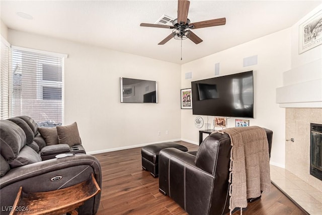 living room with dark hardwood / wood-style floors, ceiling fan, and a tiled fireplace