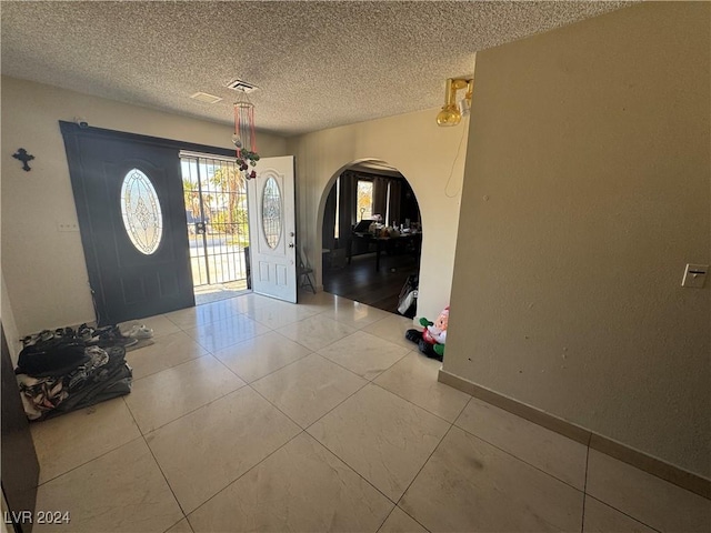 entryway with tile patterned floors and a textured ceiling