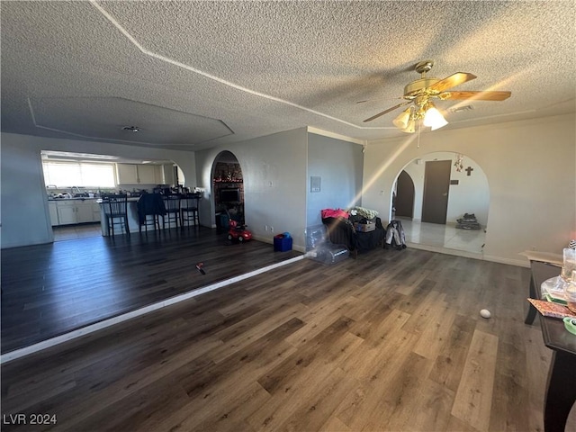 unfurnished living room featuring dark hardwood / wood-style floors, ceiling fan, and a textured ceiling