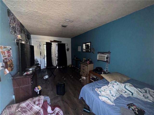 bedroom featuring a wall mounted air conditioner, a textured ceiling, and dark hardwood / wood-style floors