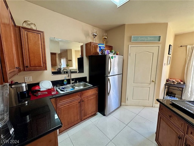 kitchen with light tile patterned floors, sink, and stainless steel refrigerator