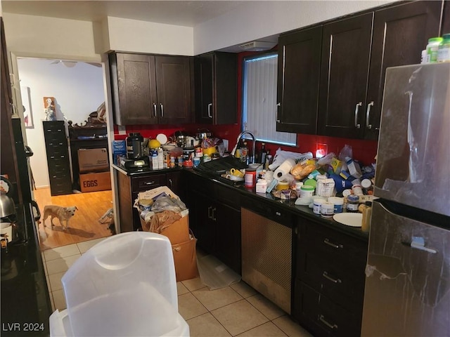 kitchen with light tile patterned flooring, dark brown cabinets, sink, and stainless steel fridge