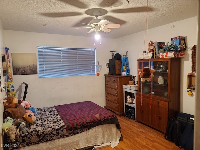 bedroom with ceiling fan, light hardwood / wood-style flooring, and a textured ceiling