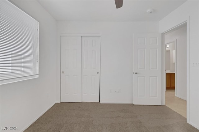 unfurnished bedroom featuring ceiling fan, light carpet, and a closet