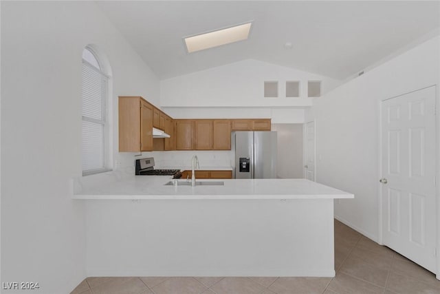 kitchen with kitchen peninsula, sink, vaulted ceiling with skylight, and appliances with stainless steel finishes