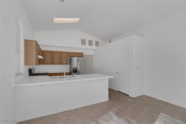 kitchen with stainless steel fridge, stove, lofted ceiling, and kitchen peninsula