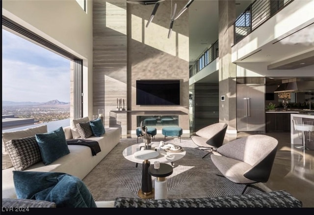 living room with exterior fireplace and a high ceiling