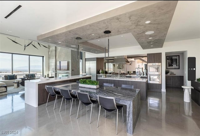 kitchen featuring island exhaust hood, stainless steel double oven, decorative light fixtures, and a spacious island