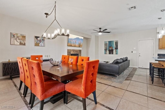 dining space with ceiling fan with notable chandelier and light tile patterned flooring