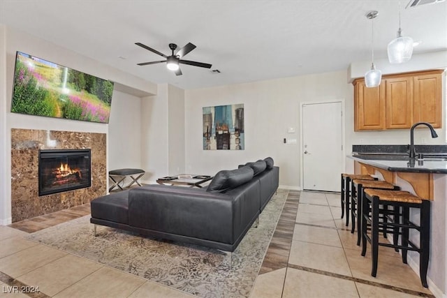 tiled living room featuring ceiling fan, sink, and a high end fireplace