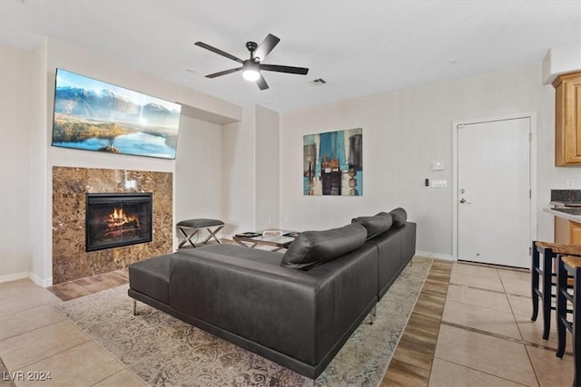 living room featuring a high end fireplace, light tile patterned flooring, and ceiling fan