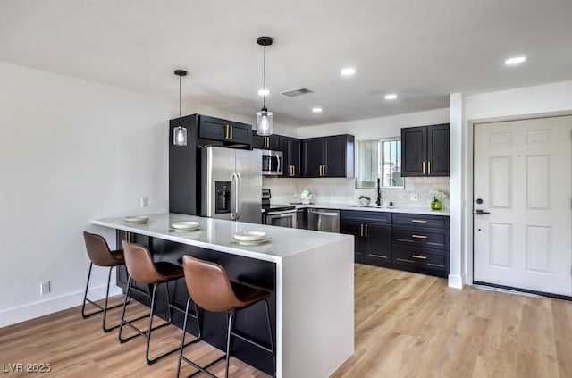 kitchen featuring appliances with stainless steel finishes, a breakfast bar, pendant lighting, sink, and kitchen peninsula