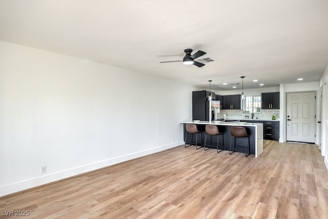 kitchen with tasteful backsplash, decorative light fixtures, light hardwood / wood-style floors, and stainless steel fridge with ice dispenser