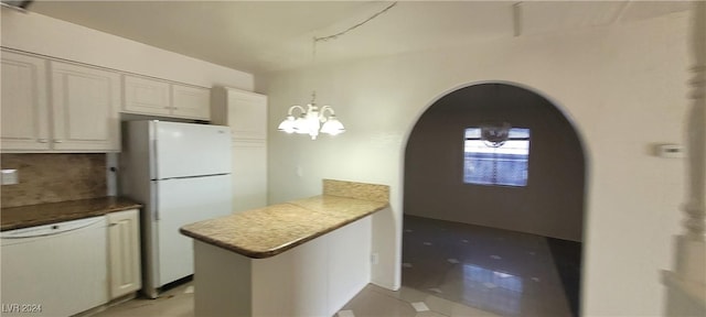 kitchen featuring white cabinetry, backsplash, kitchen peninsula, a chandelier, and white appliances