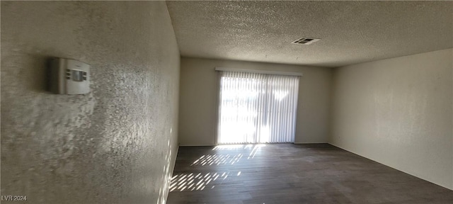 unfurnished room featuring dark hardwood / wood-style floors and a textured ceiling