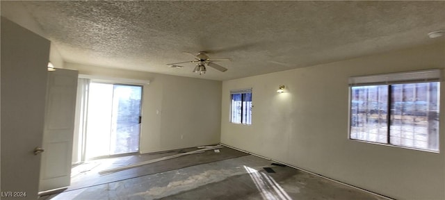 unfurnished room with ceiling fan and a textured ceiling