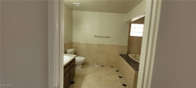 bathroom featuring vanity, tile patterned floors, toilet, tile walls, and a tub