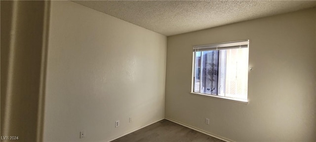 unfurnished room with a textured ceiling and dark hardwood / wood-style floors