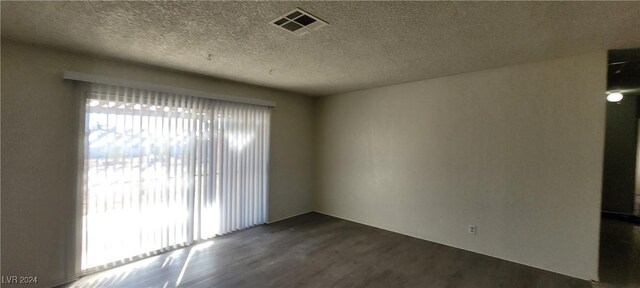 empty room featuring a textured ceiling and dark hardwood / wood-style floors