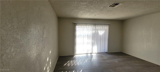 spare room featuring dark hardwood / wood-style floors and a textured ceiling