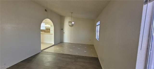 interior space with a textured ceiling, dark tile patterned flooring, and lofted ceiling