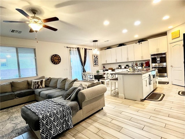 living room with ceiling fan, sink, and light hardwood / wood-style floors