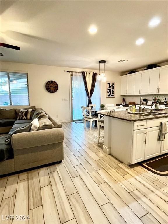 kitchen with white cabinets, a wealth of natural light, light hardwood / wood-style floors, and hanging light fixtures