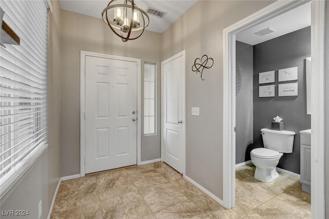 foyer featuring a wealth of natural light, light tile patterned flooring, and a chandelier