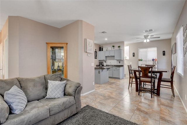 tiled living room with ceiling fan and sink