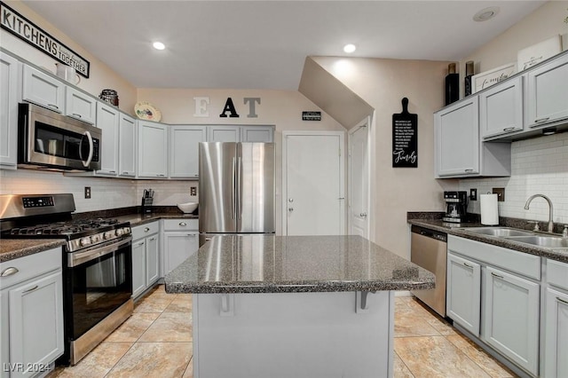 kitchen with decorative backsplash, stainless steel appliances, sink, dark stone countertops, and a kitchen island