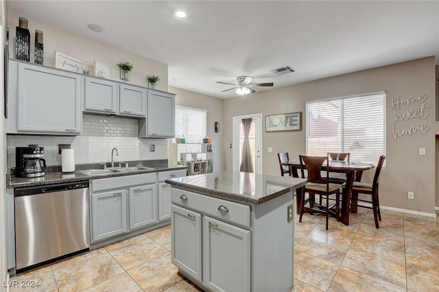 kitchen with tasteful backsplash, ceiling fan, sink, dishwasher, and a kitchen island