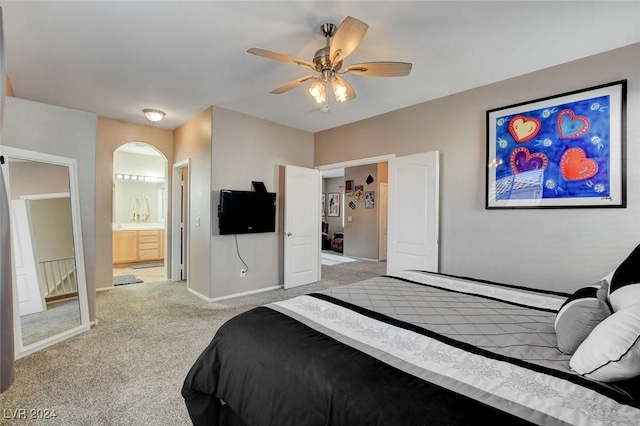 bedroom with light carpet, ensuite bathroom, and ceiling fan