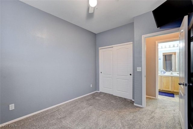 unfurnished bedroom with a closet, light colored carpet, ceiling fan, and sink