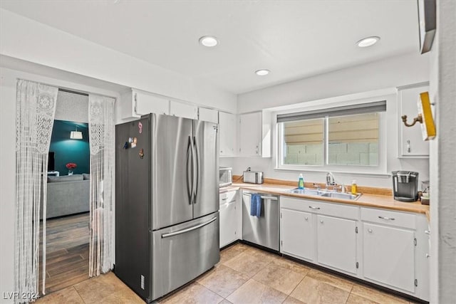 kitchen with light wood-type flooring, white cabinetry, sink, and appliances with stainless steel finishes