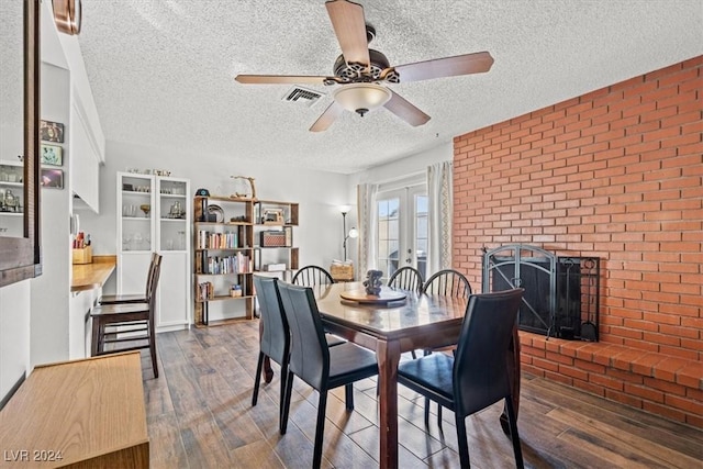 dining space featuring ceiling fan, french doors, a textured ceiling, a fireplace, and hardwood / wood-style flooring